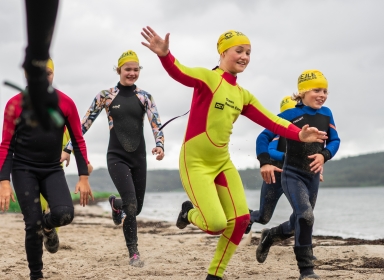 Børn i våddragter på en strand